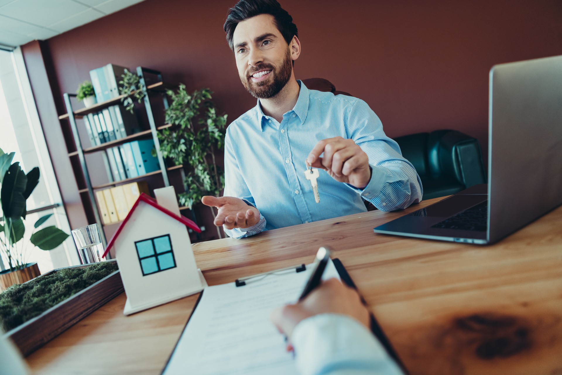 Professional discussion with real estate agent handing keys during office transaction meeting.